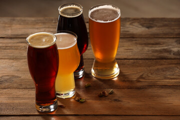 Poster - Glasses with different types of beer and pistachio nuts on wooden table