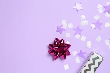 Canvas Print - Shiny confetti and festive decor on violet background, flat lay. Space for text