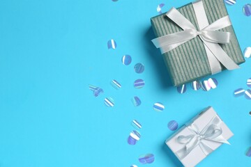 Gift boxes and shiny confetti on light blue background, flat lay. Space for text