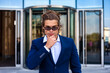 © Alex Vog - Portrait of thoughtful young businessman in blue suit and sunglasses in business district, think looking at camera. Business male near building corporate company in financial area. Copy ad text space