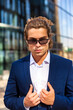 © Alex Vog - Sunny portrait of perfect businessman in blue suit and glasses near skyscrapers in business district, strong looking at camera. Stylish male in corporate company in financial area. Copy ad text space