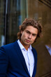 © Alex Vog - Perfect man model businessman in blue suit posing in business urban district, serious looking at camera. Portrait of stylish guy near corporate company office in financial area. Copy ad text space