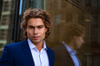 © Alex Vog - Face of elegant man model businessman in blue suit posing in business urban district, confident looking at camera. Portrait of stylish guy near corporate company in financial area. Copy ad text space