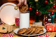 © Answer 7 - male hand holding a chocolate chip cookie soaking in milk with a christmas decorated background christmas food concept