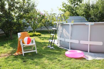 Poster - Above ground swimming pool, folding chair, towel, inflatable ring and ball in backyard