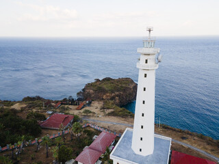 White Lighthouse on Cliff Overlooking the Endless Ocean.