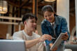 © bongkarn - A smart Asian man is working with his female colleague, reviewing her work on a digital tablet.