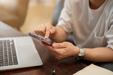 A cropped image of a man using his smartphone while sitting in a coffee shop.