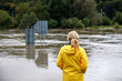 © encierro - Flooded river. Worried woman looking at overflowing water during flood. Extreme weather and natural disaster