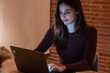 © simona - Young businesswoman working in her home office in the evening, using a laptop to conduct business and earn money. The photo illustrates telecommuting and smart working with a modern woman managing