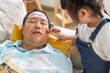 © Art_Photo - Asian father asleep on couch while little daughter playfully applies makeup on his face, funny family moment playful asian child, humor, bonding, daddy and daughter love, parenting, relaxation at home