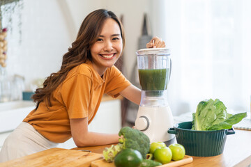 Wall Mural - Portrait of beauty healthy asian woman making green vegetables detox cleanse and green fruit smoothie with blender.young girl drinking glass of smoothie, fiber, chlorophyll in kitchen.Diet, healthy