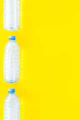 Plastic bottles with pure water on yellow background top view sp