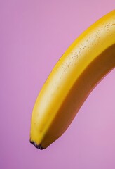 A banana is shown in a close up on a pink background. The banana is peeled and has a yellow peel