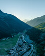 © AmazingAerialAgency - Aerial view of picturesque Cogne town nestled in the scenic Aosta Valley surrounded by majestic mountains and a winding river at sunset, Italy.