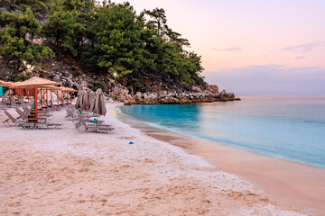 A beach with a beautiful blue ocean and a rocky cliff in the background