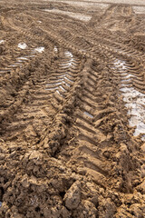 Wall Mural - plowed soil covered with snow and frost in a field with tractor tracks