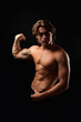 © Alex Vog - Sporty healthy man with abs muscle press showing arm biceps at black in shadow, studio shot. Portrait of handsome guy with perfect muscular sexy bare torso poses, advertising model. Copy ad text space