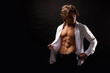 © Alex Vog - Portrait of stylish guy fashion model in unbuttoned white shirt with abs muscle press posing at shadow, looking down. Lovely man with perfect muscular sexy torso, black studio shot. Copy ad text space