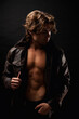 © Alex Vog - Confident young man in unbuttoned leather jacket with abs muscle press posing in black studio shadow. Portrait of perfect guy fashion model with lovely muscular sexy torso, image. Copy ad text space