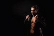 © Alex Vog - Perfect young man in unbuttoned leather jacket with abs muscle press posing in black studio shadow, strong look. Handsome guy fashion model with lovely muscular sexy torso, image. Copy ad text space
