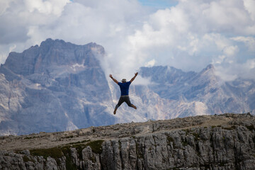 Wall Mural - Man jumping celebrating success with the view of the Dolomites mountains.