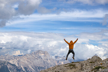 Wall Mural - Man jumping celebrating success with the view of the Dolomites mountains.