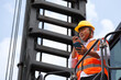 © gumpapa - Construction asian engineer using a walkie-talkie and holding a smartphone on an industrial site. dock foreman standing at warehouse logistic in cargo freight ship.