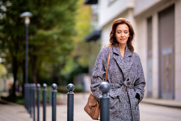 Wall Mural - Attractive mid aged woman walking outdoors in city street on autumn day