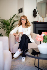 Wall Mural - Blond haired woman relaxing in an armchair in her modern home