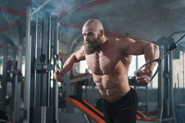 Wall Mural - Bald Caucasian bodybuilder training chest using cable crossover in gym. 