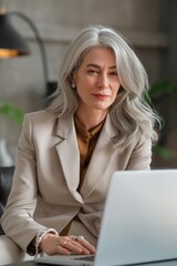 Wall Mural - A successful senior businesswoman working on a laptop in a modern office, exuding confidence and professionalism.