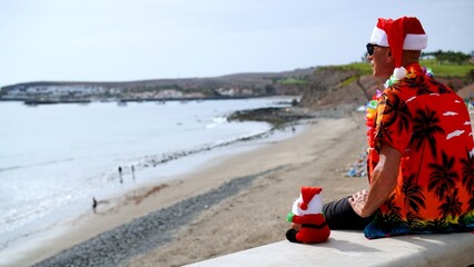 Tourist on holiday in Canary Islands celebrates Christmas on the beach with Santa Claus. Travel to places with tropical climate concepts