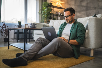 Adult man work from home on laptop seat on floor at home