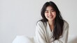 © tantawat - Cheerful Asian Model Relaxing in Cozy Flannel Pajamas on Plush White Cushion