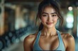 © Jane_S - A smiling young woman in athletic wear, exuding confidence and positivity during her workout at the gym, representing a healthy and active lifestyle.