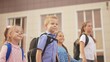 © maxximmm - back to school. a group of schoolchildren with backpacks walk next to the school. lifestyle education kids concept. schoolboy and schoolgirl going to school. a group of children walking