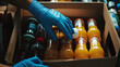 © Prasanth - A person wearing blue gloves is reaching into a box of juice bottles