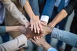 © Surachetsh - Professional business team in a close-up top view, hands stacked together to signify unity and teamwork.