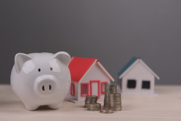 Wall Mural - Piggy bank with coin stacks and miniature houses representing home savings