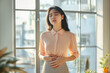 © Running opossum - Young woman is standing near the window, holding her belly and suffering from strong abdominal pain