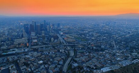 Wall Mural - Hazy panorama of Los Angeles at sunset time. Aerial perspective on the vast cityscape under orange sky.