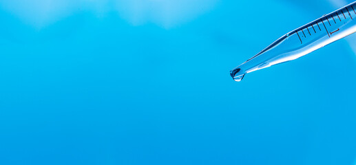 Wall Mural - macro science experiment with water drop. liquid drops from glass pipette in laboratory on blue back