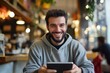 © Mykola - Man Watching Videos: Smiling Man Engrossed in Tablet PC at Cafe