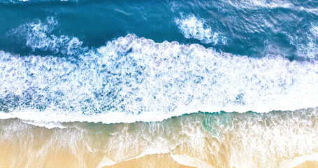 Summer beautiful waves, blue sea water. Top view from drone. Sea aerial view, tropical nature background. Beautiful sea with waves splashing. Blue ocean wave on yellow sandy beach.