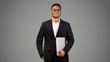 Wall Mural - Technology Concept. Confident afro guy in glasses holding laptop isolated over white background, panorama, empty space