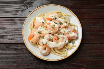 Tasty pasta with shrimps, creamy sauce and cheese on wooden table, top view