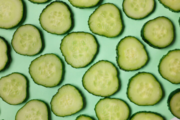 Wall Mural - Slices of fresh cucumbers on turquoise background, flat lay