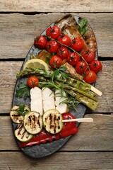 Delicious grilled vegetables and cut chicken meat on wooden table, top view