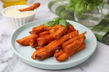 Sweet potato fries and basil on white marble table, closeup